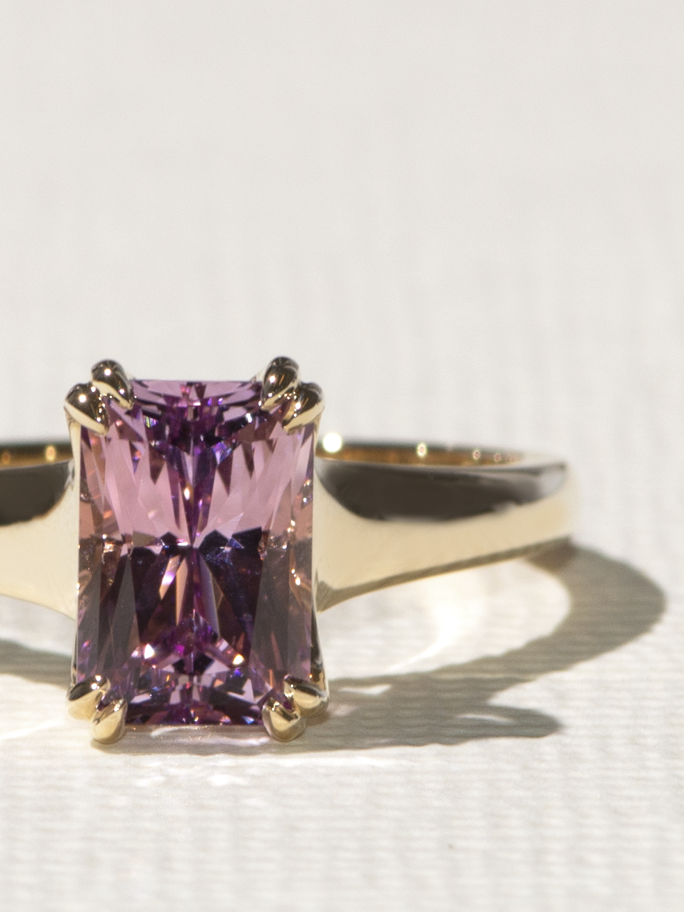 Purple lab sapphire in a gold reverse taper solitaire setting.
